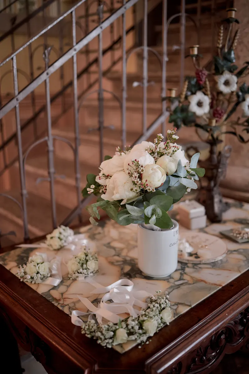 Bouquet di rose bianche su un tavolino in marmo ai piedi di una scala storica