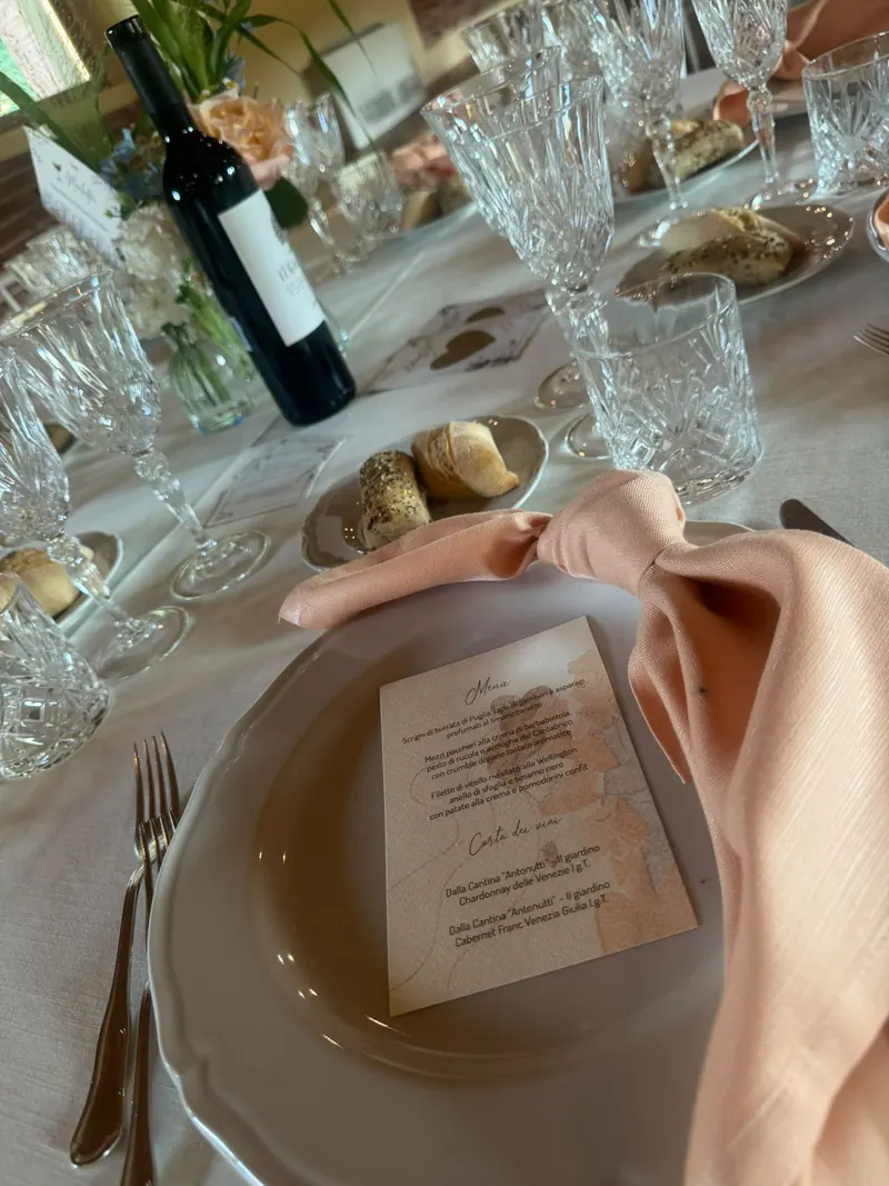 Mise en place con tovagliolo rosa e menu personalizzato per un ricevimento