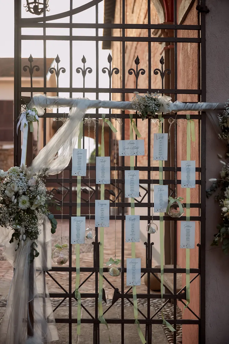 Tableau de mariage allestito su un cancello in ferro battuto decorato con fiori