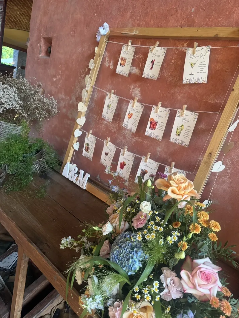 Tableau de mariage in cornice di legno con cartoncini appesi e fiori colorati